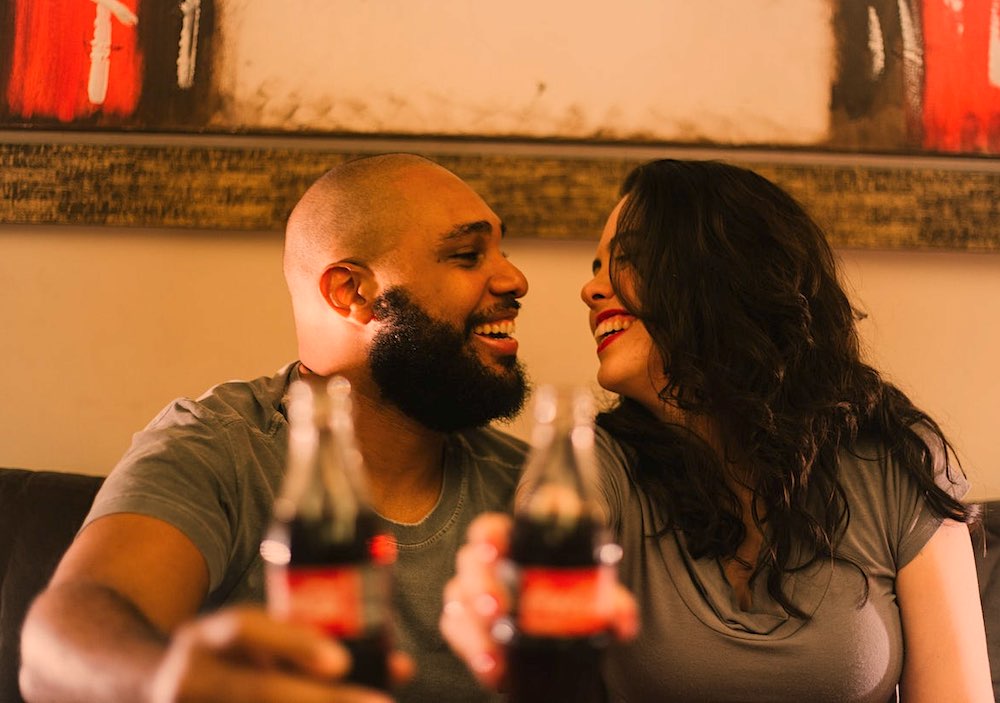 a happy man and a woman on a date while enjoying a Coca Cola in a bar