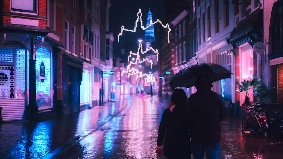 Two people walking through rainy Amsterdam at night