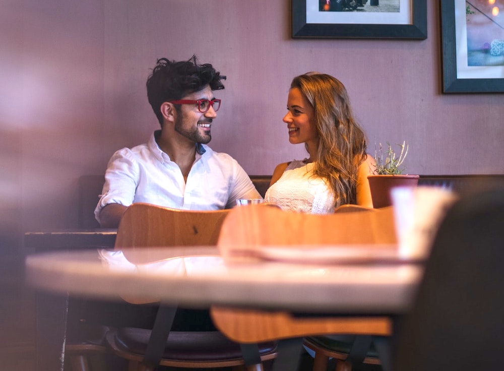 woman with blond hair and man with black hair on a date in a restaurant and flirting with each other