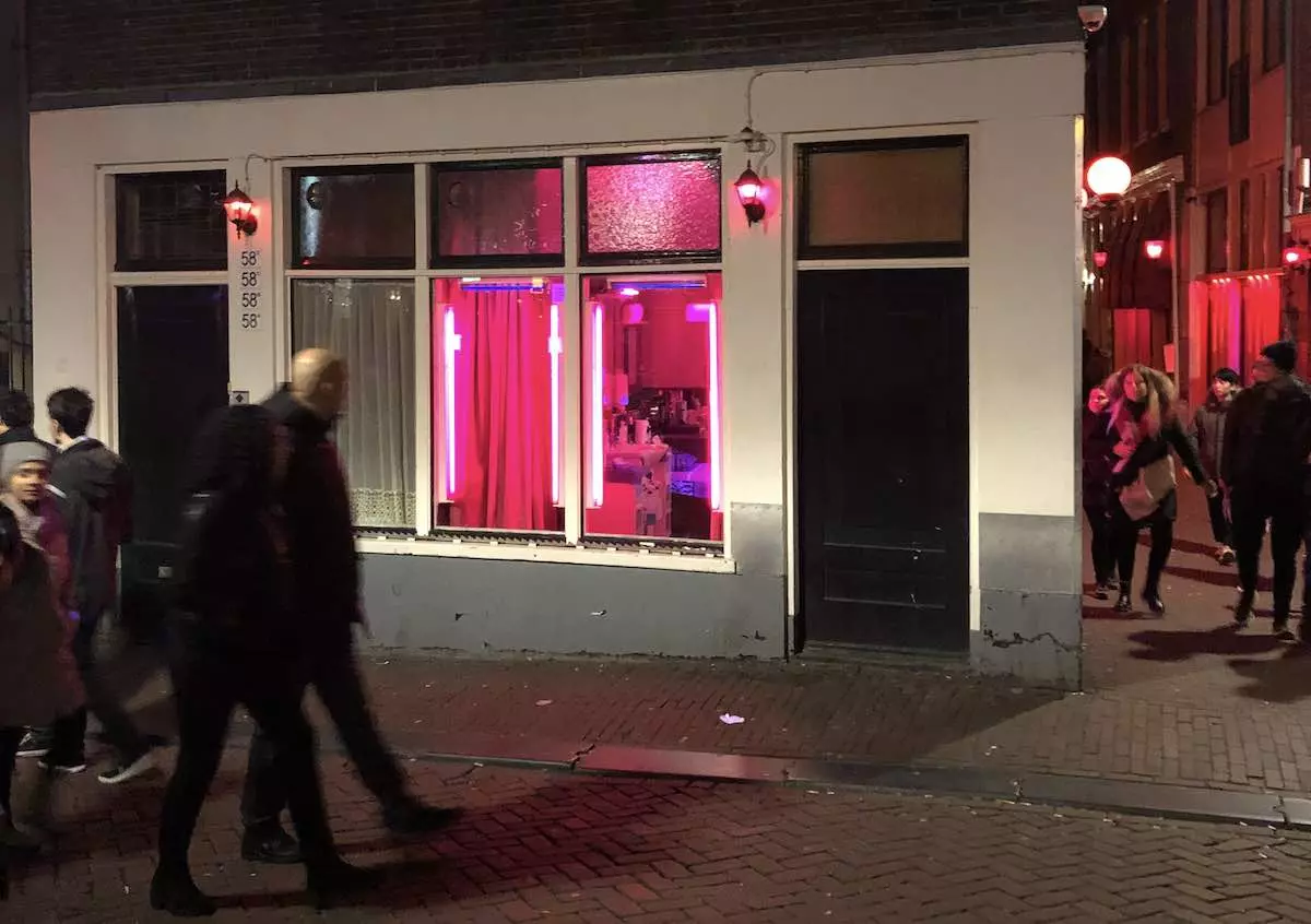 Rot beleuchtete Fensterbordelle bei Nacht im Amsterdamer Rotlichtviertel (De Wallen)