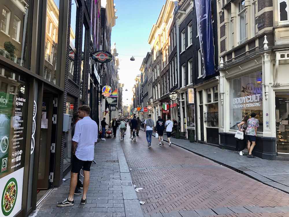 tourists on the Warmoesstraat in Amsterdam and shops on the left & right side.