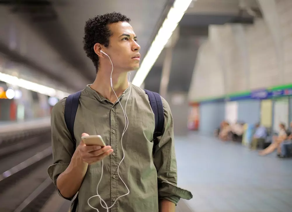 man in a green shit listening to an audio tour while holding his smartphone