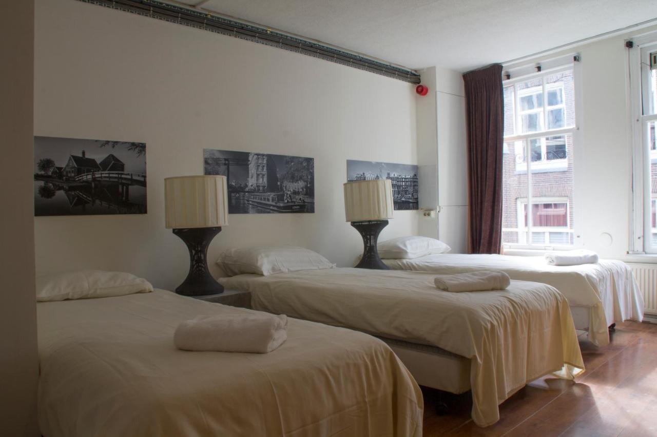 a hotel room from Hotel 55 in Amsterdam show 3 one person beds, white sleeves and simple interior