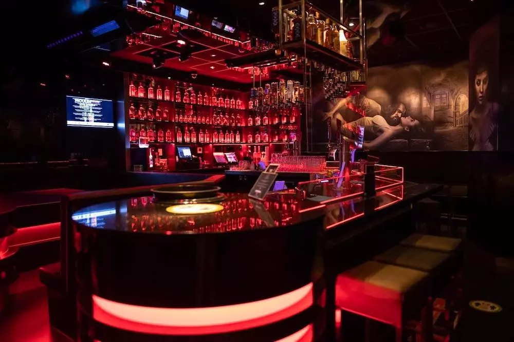 A red-lit bar inside an Amsterdam Red Light District venue, where drinks add up fast