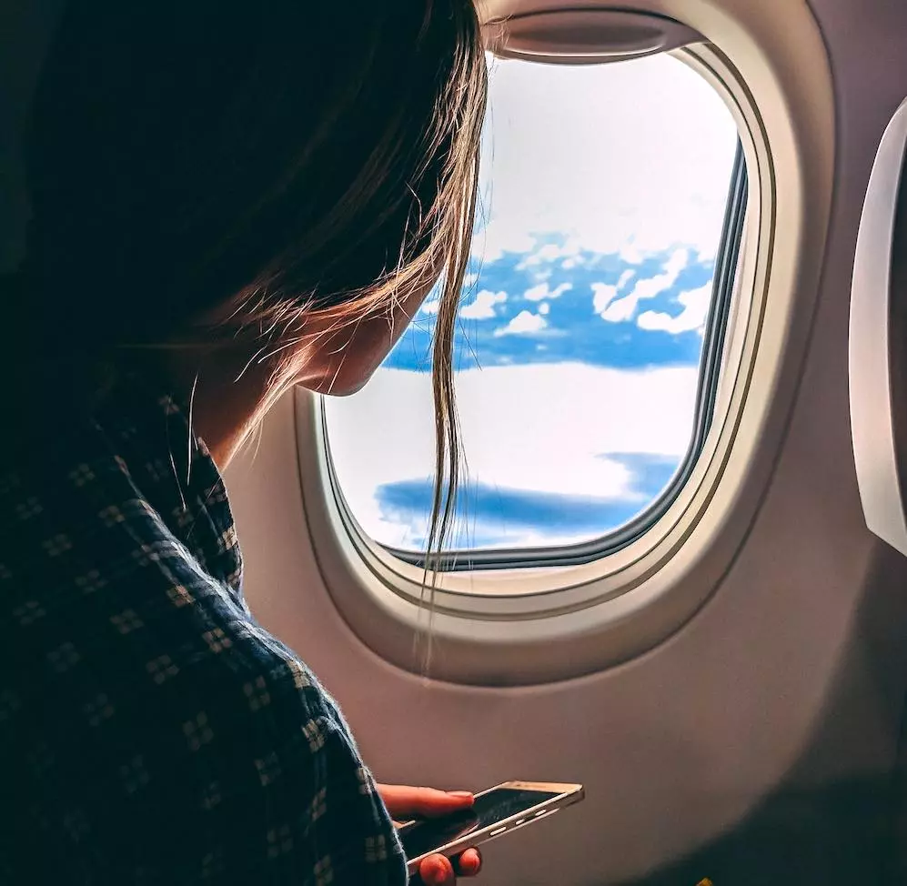 woman sitting in an airplane holding her iPhone while watching out the window.
