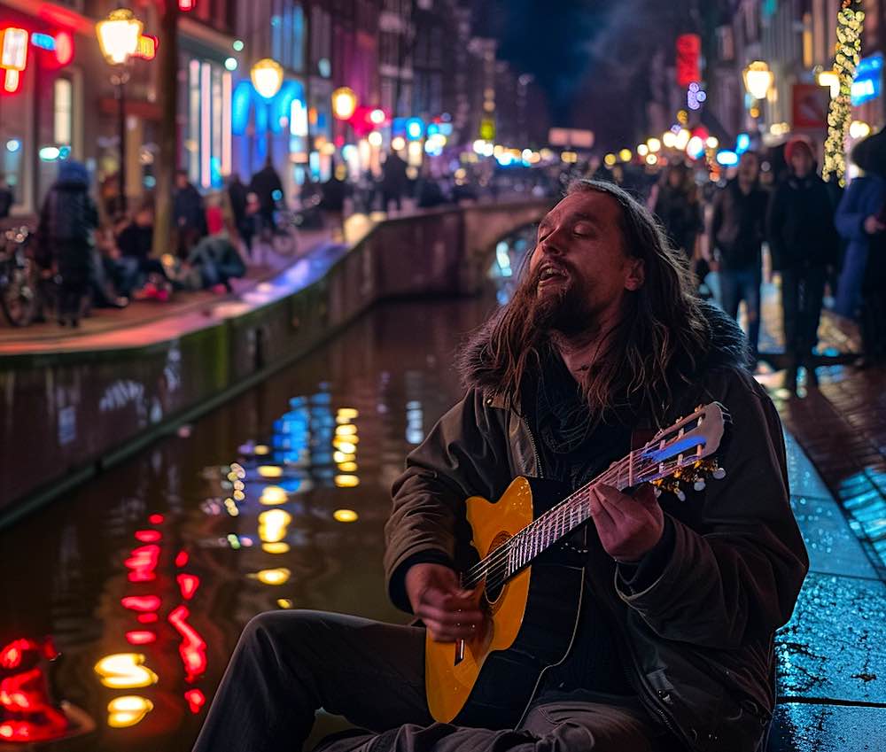 a male street artist singing a song with his guitar on the Oudezijds Achterburgwal in Amsterdam Red Light District