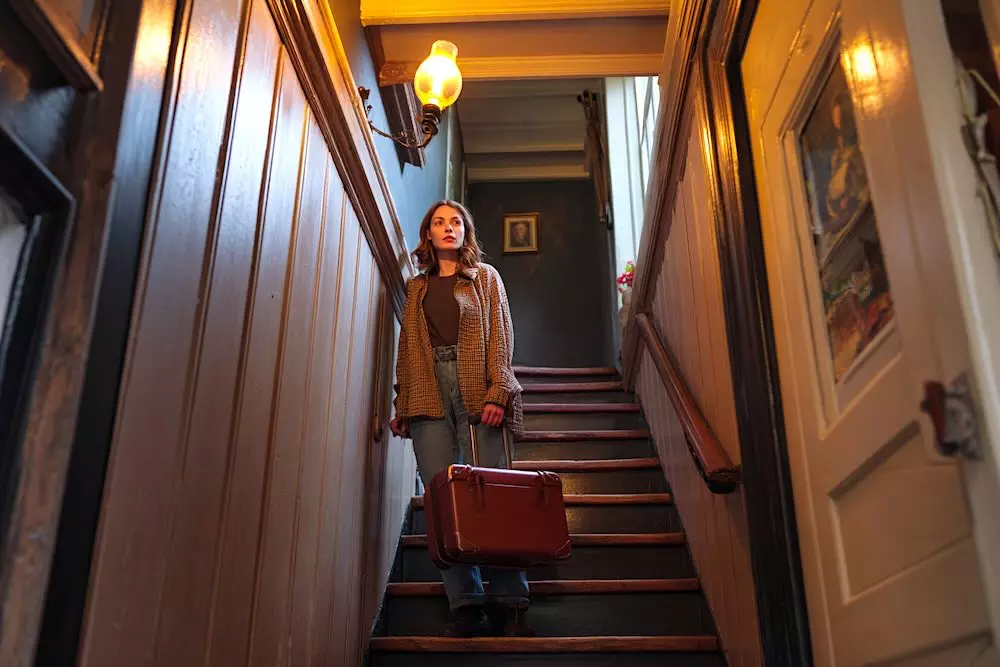 a woman with suitcase standing on a steep staircase in Amsterdam