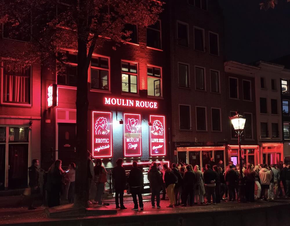 the Oudezijds Achterburgwal at night in Amsterdam Red Light District showing the front of Moulin Rouge 