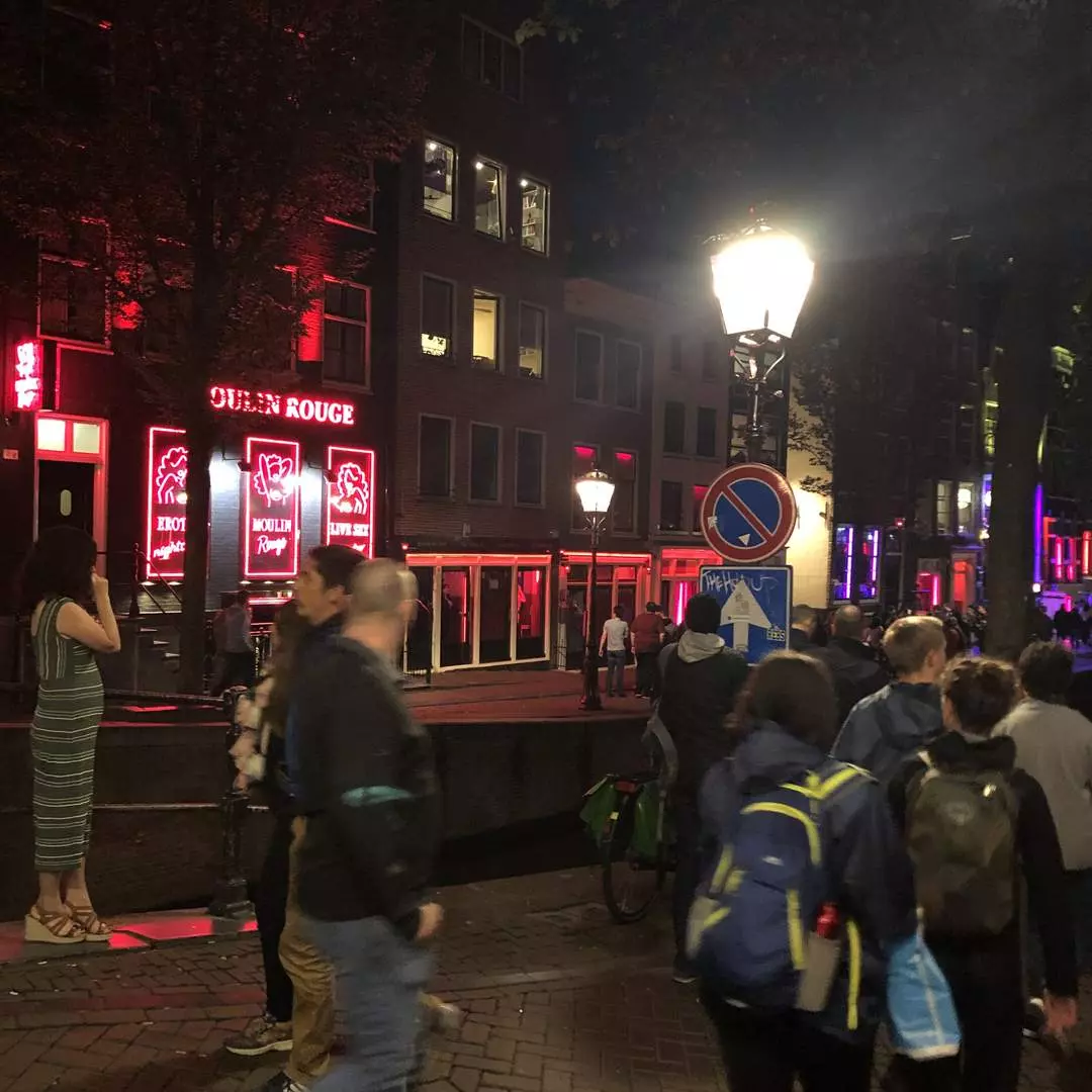 Das leuchtende Neonschild und die Fassade des Moulin Rouge Amsterdam bei Nacht an der Oudezijds Achterburgwal im Rotlichtviertel