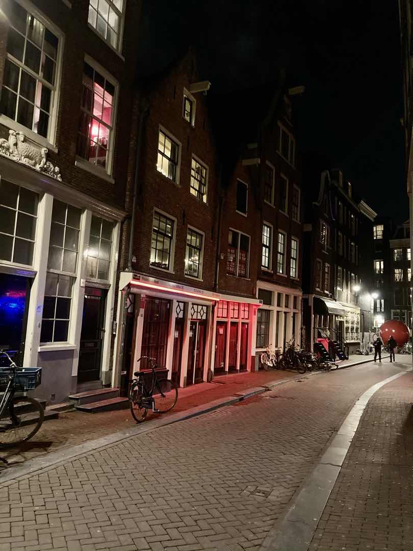 Blue-lit and red-lit window brothels on a De Wallen street at night in Amsterdam’s Blue Light District.